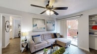 Located at 10730 Glenora Dr in Houston, TX, this single-story, one-bedroom, one-bathroom home offers a thoughtfully arranged floor plan that maximizes every inch of its compact footprint. Wood-style flooring flows throughout, complementing the neutral color palette and creating a cohesive, modern aesthetic.

The living room is a bright and welcoming space, featuring a ceiling fan with light fixture and a sliding glass door that opens to a private outdoor patio, allowing natural light to fill the room. Built-in shelving adds both functionality and character to the area.

Adjacent to the living room, the dining area accommodates a full-sized dining table and benefits from a window that brings in additional natural light. The kitchen is equipped with white cabinetry, a light stone-finish peninsula countertop, stainless steel appliances including a microwave and range hood, a black refrigerator, and track lighting overhead. A dedicated laundry area is conveniently accessible from the kitchen.

The generously sized primary bedroom includes a ceiling fan, a natural light-providing window, and direct access to the bathroom. A walk-in closet offers ample storage. The bathroom features wood-style flooring and a shower/tub combination, completing this well-appointed home.