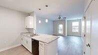 Located at 419 Donald Driver Way in Green Bay, WI, this well-appointed one-bedroom, one-bathroom unit offers a thoughtfully designed single-floor layout. The open-concept kitchen flows seamlessly into the living area, creating a bright and connected living space. The kitchen is outfitted with white shaker-style cabinetry, granite-look countertops, a peninsula with an undermount sink, and black appliances including a refrigerator, electric range, and over-the-range microwave. Pendant lighting and light wood-style flooring add a modern, polished touch. The living room features a ceiling fan, a private entry door, and multiple windows that bring in natural light and outdoor views. The bedroom offers plush carpeting, a ceiling fan, and a window overlooking the surrounding area. The bathroom includes a wide vanity with ample storage, a large mirror, and a tub/shower combination. A dedicated laundry area with a stacked full-size washer and dryer provides added convenience. A hallway connects the main living spaces with closet storage nearby. The unit features a neutral color palette and clean modern finishes throughout, creating a comfortable and functional living environment.