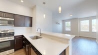 Located at 2275 E 89th St in Cleveland, Ohio, this multi-floor residence offers two bedrooms, one bathroom, and a well-planned layout spread across three levels. The main living floor features an open-concept kitchen and living room finished with light hardwood flooring. The kitchen stands out with rich dark espresso cabinetry, white countertops, a peninsula with pendant lighting, and a full suite of stainless steel appliances including a refrigerator, range, and built-in microwave. Recessed lighting adds a clean, modern touch overhead. The living area benefits from multiple windows that invite generous natural light and views of the surrounding neighborhood. A wall-mounted mini-split system provides efficient climate control throughout. The upper floor houses both bedrooms, each carpeted for comfort. The spacious primary bedroom features a ceiling fan with light fixture, a double-door closet, and large windows that brighten the room. The second bedroom is similarly well-lit with ample natural light. The shared full bathroom is finished with tile flooring and includes a tub/shower combo with white tile surround. Two staircases connect the floors, and a dedicated closet provides additional storage. Clean white walls and consistent finishes throughout give the residence a fresh, move-in-ready feel.