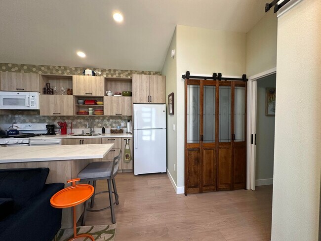 Área de cocina y armario con puertas de madera con lavadora/secadora apiladas de tamaño completo detrás - 1490 Ash St