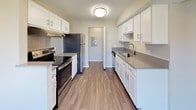 The Durham Deluxe is a two-story, 3-bedroom, 3-bathroom residence located in Ann Arbor, Michigan, offering a well-organized layout across two levels. The galley-style kitchen is outfitted with stainless steel appliances, white shaker cabinetry, gray quartz-style countertops, a tile backsplash, and wood-style flooring—providing a clean, functional workspace. A dedicated in-unit laundry area with full-size washer and dryer hookups and overhead shelving adds practical convenience.

The upper level features a dramatic vaulted ceiling that rises above the open living area, lending a sense of spaciousness and architectural character. Natural light filters in through multiple windows, brightening the carpeted living and bedroom spaces. Each of the three bedrooms is generously proportioned with plush carpet and window views of the surrounding community.

All three bathrooms are finished consistently with white cabinetry, gray countertops, wood-style vinyl flooring, and glass-enclosed walk-in showers. One bathroom features an elongated vanity and ample towel bar storage, while another offers a layout conducive to a private en-suite experience. The neutral color palette and cohesive finishes throughout create a clean, modern ambiance suited to everyday living.