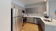 This single-floor residence in Rahway, NJ offers a thoughtfully designed layout comprising one bedroom, one bathroom, and a versatile den. The open-concept living and dining area is bathed in natural light from large windows fitted with horizontal blinds, and features warm wood-tone flooring that flows throughout the space. The living area provides a comfortable, modern atmosphere accented by neutral tones and stylish décor elements.

The kitchen is outfitted with contemporary textured cabinetry in a warm gray finish, sleek white countertops, and a full suite of stainless steel appliances including a refrigerator, range, microwave, and dishwasher. Ample upper and lower cabinet storage ensures excellent functionality.

The bedroom is generously sized with large windows that invite natural light, complemented by wood flooring and a calming neutral color palette. The den offers additional flexible living space, ideal for a home office or guest area.

The bathroom features a clean, modern design with wood-tone cabinetry, a white vanity countertop, a wall-mounted storage cabinet, and a separate shower area with light-toned tile flooring. Throughout the residence, the consistent use of natural materials, neutral hues, and modern fixtures creates a cohesive and inviting atmosphere.