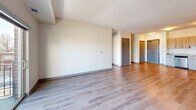 This well-appointed two-bedroom, two-bathroom unit at 835 W Broadway Ave in Minneapolis offers a thoughtfully designed single-floor layout with a clean, modern aesthetic throughout. The open-concept living and kitchen area serves as the heart of the home, featuring warm wood-tone luxury vinyl plank flooring that flows seamlessly between spaces. The kitchen is equipped with light wood cabinetry, granite-style countertops, and a full suite of stainless steel appliances, including a refrigerator, range, microwave, and dishwasher. The spacious living room is filled with natural light and provides direct access to a private balcony through sliding glass doors, offering views of the surrounding Minneapolis cityscape. Both bedrooms are finished with plush carpet, large windows that bring in ample natural light, and dedicated closets for storage. The generously sized primary bedroom provides a comfortable retreat with room to spare. Each bathroom features white shaker-style cabinetry, granite-topped vanities, tub/shower combinations, and wood-look flooring, maintaining a consistent, polished finish. The neutral color palette and clean lines throughout the unit create a bright, modern ambiance suitable for a variety of living styles.