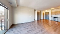 This well-appointed two-bedroom, two-bathroom unit at 835 W Broadway Ave in Minneapolis offers a thoughtfully designed single-floor layout with a clean, modern aesthetic throughout. The open-concept living and kitchen area serves as the heart of the home, featuring warm wood-tone luxury vinyl plank flooring that flows seamlessly between spaces. The kitchen is equipped with light wood cabinetry, granite-style countertops, and a full suite of stainless steel appliances, including a refrigerator, range, microwave, and dishwasher. The spacious living room is filled with natural light and provides direct access to a private balcony through sliding glass doors, offering views of the surrounding Minneapolis cityscape. Both bedrooms are finished with plush carpet, large windows that bring in ample natural light, and dedicated closets for storage. The generously sized primary bedroom provides a comfortable retreat with room to spare. Each bathroom features white shaker-style cabinetry, granite-topped vanities, tub/shower combinations, and wood-look flooring, maintaining a consistent, polished finish. The neutral color palette and clean lines throughout the unit create a bright, modern ambiance suitable for a variety of living styles.