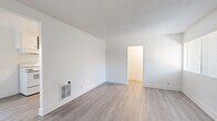 Located at 16131 Cornuta Avenue in Bellflower, CA, this efficiently designed one-bedroom, one-bathroom unit offers a well-organized single-floor layout comprising a living room, kitchen, bedroom, bathroom, and hallway. The living room is bright and open, featuring light gray wood-style laminate flooring, crisp white walls, a textured ceiling, and a wall-mounted heating unit. Natural light filters in through window blinds, enhancing the clean, airy atmosphere. A white entry door with a classic knob adds a simple, welcoming touch.

The galley-style kitchen is thoughtfully appointed with white cabinetry, granite-look countertops, a double-basin sink, a white electric range with overhead hood, and a full-size refrigerator. A window above the range area allows natural light into the cooking space, complementing the matching laminate flooring that flows throughout the common areas.

The bedroom offers a comfortable and quiet retreat, finished with plush neutral carpet, white walls, a window with blinds, and a flush-mount ceiling light fixture. The bathroom is clean and functional, featuring a full soaking tub with a tiled surround in a neutral stone pattern, a wall-mounted showerhead, a white vanity with a sink, and a mirror.