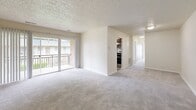 Located at 2018 Cunningham Dr in Hampton, Virginia, this single-floor, 3-bedroom, 2-bathroom home offers a well-organized and functional layout. The combined living and dining area is bright and open, featuring soft carpet flooring, a textured ceiling, and sliding glass doors that lead to a private balcony with outdoor views — bringing in generous natural light. The kitchen is thoughtfully appointed with rich dark wood cabinetry, dark granite countertops, stainless steel appliances including a refrigerator and oven, and light hardwood-style flooring, complemented by a window that enhances the sense of openness. The three bedrooms are carpeted and finished with neutral tones, creating a calm and comfortable atmosphere. The generously sized primary bedroom features two closets and a large window. Each additional bedroom also includes closet space, and the home offers an impressive total of six closets, ensuring ample storage throughout. The two bathrooms are cleanly finished, with one showcasing a tiled tub surround featuring white subway tiles and a decorative mosaic border accent. A dedicated laundry area and a connecting hallway round out this efficiently designed home.