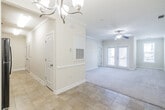 This single-floor residence offers a thoughtfully designed layout that balances comfort and functionality throughout. The spacious living area is finished with plush carpeting and features elegant crown molding, a ceiling fan with integrated lighting, and direct access to a private balcony through glass-panel doors with slatted blinds, allowing generous natural light to fill the space. An adjacent dining area is distinguished by classic wainscoting along the lower walls, tile flooring, and a brushed nickel chandelier that adds a refined finishing touch. The kitchen is outfitted with warm-toned wood cabinetry, granite countertops, a stainless steel sink, a dishwasher, and black appliances including a full-size refrigerator, all complemented by durable tile flooring. A bedroom provides a calm retreat with soft carpeting, neutral wall tones, crown molding, and a window that brings in natural light. The bathroom is well-appointed with a vanity featuring granite countertops and rich wood cabinetry, a large mirror, tile flooring, and a full-size soaking tub with an overhead shower. Throughout the unit, consistent use of crown molding, neutral warm tones, and quality finishes creates a cohesive and inviting ambiance.