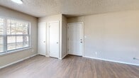 Located at 315 SE Warwick Way in Lawton, Oklahoma, this single-story, one-bedroom, one-bathroom home offers a practical and well-organized layout across a compact but functional floor plan. The living room greets you upon entry with durable wood-look laminate flooring, neutral beige walls, and a textured ceiling. Natural light filters in through a window, and the space includes a built-in thermostat and ventilation. Two interior doors near the entry provide convenient closet storage directly off the main living area. A hallway connects the living room to the remaining spaces, maintaining a smooth flow throughout the home. The bedroom is a comfortable retreat, finished with plush wall-to-wall carpeting, a ceiling fan with light fixture, and a window that brings in natural light with outdoor views. A dedicated walk-in closet with built-in shelving offers ample storage. The bathroom is clean and efficiently designed, featuring a combined shower and tub, a toilet, a vanity with countertop space, and an overhead cabinet for additional storage. Wood-look flooring carries through into the bathroom, tying the space together. Throughout the home, textured ceilings and neutral tones create a consistent, understated aesthetic.