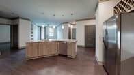 Located at 7085 Sentara Pl in Alpharetta, GA, this single-floor residence offers a thoughtfully designed layout with modern finishes throughout. The open-concept kitchen is a standout feature, showcasing light wood flat-front cabinetry, granite countertops, a marble-style tile backsplash, and a full suite of stainless steel appliances including a French door refrigerator, electric range, built-in microwave, and dishwasher. A decorative wine rack adds a refined touch above the upper cabinetry, while pendant lighting over the kitchen island enhances the space's contemporary aesthetic. Rich, dark hardwood-style flooring flows consistently throughout the unit, grounding each room with warmth and cohesion. The bedrooms are generously proportioned, each featuring ceiling fans, crown molding with gray trim accents, and natural light from windows with blinds. The primary suite connects to a well-equipped en-suite bathroom featuring a glass-enclosed shower, a soaking tub with tiled surround, granite-topped vanity, and access to a walk-in closet outfitted with wire shelving systems. A secondary bathroom includes a tub-shower combo with tiled walls and granite vanity detailing. The unit's neutral color palette, consistent trim work, and quality fixtures create a clean, modern living environment.