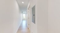 This 1-bedroom, 1-bathroom unit in Everett, MA offers a clean, modern interior designed with simplicity and functionality in mind. The single-floor layout is organized efficiently, with a spacious living area, two hallway passages, and a full bathroom.

The living area is bright and airy, bathed in natural light streaming through multiple double-hung windows that frame views of surrounding greenery. Light-toned hardwood flooring runs throughout, complementing the crisp white walls and creating a warm, contemporary atmosphere. Recessed lighting adds to the well-lit feel of the space.

The bedroom area benefits from large windows on two walls, allowing sunlight to pour in from multiple angles. A wall-mounted mini-split HVAC unit ensures year-round climate comfort. The clean, neutral palette throughout provides a versatile canvas for any style of furnishing.

The bathroom is finished to a high standard, featuring a frameless glass-enclosed walk-in shower with white tile surround, brushed nickel hardware, and a sleek, modern door. White flooring and walls carry the bright, cohesive aesthetic from the rest of the unit into this space seamlessly.

Overall, this unit presents a thoughtfully designed, move-in-ready space with modern finishes, abundant natural light, and a clean architectural aesthetic suited for comfortable everyday living in Everett, MA.