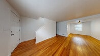 Located at 283 Cooper Pl in New Haven, CT, this multi-level home offers 2 bedrooms and 1 bathroom across three well-organized floors. Rich hardwood flooring flows throughout the main and upper levels, lending warmth and continuity to the interior. The main floor features a combined living and dining area bathed in natural light from large windows that frame views of the surrounding greenery. A staircase anchors the space, connecting all three levels with ease. The kitchen stands out as a highlight of the home, featuring white shaker cabinetry, dark granite countertops, a mosaic tile backsplash in cool tones, stainless steel appliances including a dishwasher and range, and light wood-look flooring. A door in the kitchen provides convenient exterior access. Upstairs, two bedrooms offer clean, bright spaces with hardwood floors, natural light from windows, and ample closet access. The primary bedroom is generously sized with multiple doorways leading to closets. The full bathroom is appointed with a soaking tub and floor-to-ceiling wood-look tile surround in neutral tones with brushed gold fixtures. A finished basement adds additional flexible space to the home. Throughout, the clean white walls and consistent finishes create a cohesive, move-in-ready aesthetic.