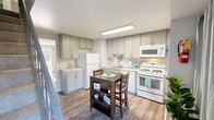 Located at 32 Sorgen Ct in Middle River, MD, this two-story, two-bedroom, one-bathroom home is thoughtfully laid out across two equally sized floors. The main level opens into a bright and welcoming living room finished with wood-look vinyl flooring, neutral gray walls, and large sliding glass doors that flood the space with natural light and provide direct access to an outdoor balcony. A staircase connects the main level to the upper floor, keeping the layout functional and easy to navigate. The kitchen is efficiently designed with gray shaker-style cabinetry, light countertops, a stainless steel sink, and white appliances including a gas range, microwave, refrigerator, and dishwasher. Wood-look flooring continues throughout the kitchen, which also accommodates a small dining area. Upstairs, both bedrooms feature soft carpeting and neutral walls. The primary bedroom offers a comfortable, well-proportioned layout with natural light from a window. The second bedroom includes access to a dedicated closet with built-in shelving. The full bathroom on the upper level includes a tub-shower combination with clean white surroundings. A hallway connects the upstairs rooms, completing this well-organized and move-in-ready home.
