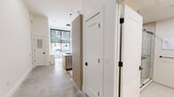 This thoughtfully designed studio unit at 24–46 Bank St in New Britain, Connecticut, maximizes every square foot through smart, modern architecture and carefully considered finishes. The single-floor layout integrates living, sleeping, and kitchen functions within a cohesive open plan, finished with polished concrete floors that lend an urban, contemporary character throughout.

The kitchen is a standout feature, defined by tall ceilings that amplify the sense of volume. Light wood cabinetry pairs with a quartz-topped island that accommodates seating for multiple guests. Stainless steel appliances, a deep undermount sink with a matte black faucet, and pendant globe lights overhead complete the refined, functional design. Open shelving adds visual interest without overwhelming the space.

The living area benefits from a large, floor-to-ceiling window that frames street-level views of downtown New Britain and floods the interior with natural light. A built-in murphy bed and integrated shelving system allow the space to serve dual purposes seamlessly.

The bathroom features a floating wood vanity with a white quartz countertop, an undermount sink, matte black fixtures, and a large frameless mirror with linear overhead lighting. White panel doors with matte black hardware and a double-door closet provide ample storage and a clean, cohesive aesthetic throughout.