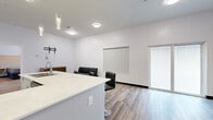 This well-designed 1-bedroom, 1-bathroom single-floor unit offers a clean, modern aesthetic throughout. The open-concept living area and kitchen flow seamlessly together, centered around a large white quartz kitchen island with bar seating for three. The kitchen is fully equipped with stainless steel appliances — including a range, refrigerator, and built-in microwave — white cabinetry, and elegant pendant lighting overhead. Light wood-style flooring runs throughout the main living spaces, complementing the crisp white walls and creating a bright, airy ambiance. The living area provides comfortable space for relaxing or entertaining, with a sliding glass door that invites natural light. The spacious primary bedroom features a large window with outdoor views, a neutral color palette, and a built-in headboard wall panel. Two closets provide ample storage. The bathroom offers a refined finish with a white vanity, white quartz countertop, a backlit LED mirror, and soft blue accent walls paired with light tile flooring. The overall design is contemporary and functional, making efficient use of every square foot in this thoughtfully laid-out unit.