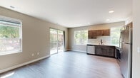 This single-floor residence showcases a thoughtfully designed layout with a cohesive modern aesthetic throughout. The open-concept kitchen and living area serves as the central hub of the space, where warm, dark-stained wood cabinetry contrasts with crisp white quartz countertops. Stainless steel appliances, including a refrigerator, electric range, built-in microwave, and dishwasher, provide a fully equipped cooking environment. A matte black faucet and sink add a contemporary accent. Large windows flood the kitchen and living area with natural light, offering views of surrounding greenery, while a sliding glass door opens directly onto a private balcony.

The bedrooms feature plush carpeting, ceiling fans, and windows overlooking wooded outdoor scenery. At least one bedroom includes a dedicated walk-in closet with built-in shelving for organized storage. The bathrooms continue the design language found throughout the unit, with dark wood vanity cabinetry, white countertops, matte black hardware, and wood-look tile flooring.

Hallways are finished with Craftsman-style paneled doors fitted with matte black hardware, complementing the neutral warm-gray wall tones and light hardwood-style flooring found in the main living areas. The overall ambiance is clean, contemporary, and move-in ready.
