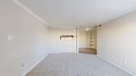 This 610 square foot single-story residence in Tomball, Texas, offers a well-designed living space with one bedroom and two bathrooms. The home's layout efficiently utilizes its compact footprint, featuring a 150 square foot primary bedroom, a living room, hallway, and closet space.

The interior is characterized by a neutral color palette, with beige walls and white trim creating a bright, spacious atmosphere. Plush carpeting extends throughout the main living areas and bedroom, providing comfort underfoot. Ceiling fans with integrated lighting fixtures enhance both air circulation and illumination.

The living room is adorned with a large window, allowing natural light to flood the space. A partially open concept design connects the living area to what appears to be a small kitchen or dining nook, separated by a half wall. Built-in shelving adds functional storage and display options.

The bathroom showcases modern fixtures, including a navy blue vanity with a white countertop, complemented by a full-width mirror and contemporary lighting. Wood-look vinyl flooring in the bathroom adds a touch of warmth and durability.

Crown molding throughout adds a refined touch to the space, while the neutral backdrop allows for easy personalization. The property's efficient design and thoughtful amenities make it an ideal option for those seeking a low-maintenance yet comfortable living environment.