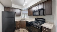 Located at 949 Atlantic Ave in Hoffman Estates, IL, this well-appointed one-bedroom, one-bathroom unit offers a thoughtfully designed single-floor layout. The open living room is bright and welcoming, featuring rich hardwood-style flooring, a ceiling fan, and large windows along with a set of French doors that flood the space with natural light and provide views of the surrounding greenery. A pass-through window connects the living room to the kitchen, maintaining an open, airy feel throughout.

The kitchen is a standout feature, showcasing dark espresso cabinetry paired with granite-style countertops, a classic subway tile backsplash, and a full suite of black appliances including a gas range, built-in microwave, and refrigerator. The corner sink layout maximizes workspace efficiency, and a window above the sink adds natural light.

The generously sized bedroom features plush wall-to-wall carpeting, neutral tones, and a window offering natural light and outdoor views, creating a calm and restful retreat.

The bathroom is clean and functional, featuring a dark wood vanity with granite-style countertop, a large mirror, and a full tub/shower combo with white tile surround. Hardwood-style flooring carries through the bathroom, tying the unit's aesthetic together cohesively.