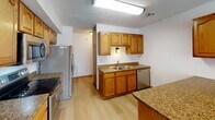 Located on Queens Court in Grand Forks, North Dakota, this two-floor home offers a practical and well-organized layout designed for comfortable everyday living. The main living area is generously proportioned, featuring wall-to-wall carpet, neutral white walls, and a textured ceiling. A carpeted staircase connects the two floors, and a paneled wood door provides access to additional spaces, contributing to the home's warm, functional character throughout.

The kitchen is equipped with rich oak cabinetry, granite-look countertops, and light wood-style flooring. Stainless steel appliances, including a refrigerator, electric range, and dishwasher, are integrated alongside a double-basin sink. Ample upper and lower cabinetry provides generous storage and prep space.

Bedrooms are carpeted and well-sized, each featuring textured ceilings and natural light from windows with blinds. At least one bedroom includes a built-in closet with a rod and shelving system behind paneled bifold doors.

The bathroom features dark stone-tile flooring, a granite-top vanity with an undermount sink, a full soaking tub with shower, and a conveniently adjoined laundry area with washer and dryer hookups and overhead cabinet storage. A half bath with a granite vanity and large mirror is also present.