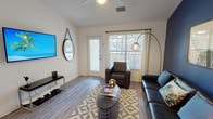 This well-appointed 4-bedroom, 4-bathroom single-story residence offers a generous and functional layout designed to accommodate comfortable shared or family living. The living room serves as the heart of the home, featuring wood-look flooring, a ceiling fan, and large windows that flood the space with natural light while providing views of the outdoors. A bold accent wall adds a striking design element, complementing the room's modern aesthetic. The kitchen is outfitted with white shaker-style cabinetry, granite-look countertops, and black appliances, creating a clean and contemporary cooking space. Each of the four bedrooms is thoughtfully sized, offering carpeted flooring, ceiling fans, and windows with outdoor views that bring in ample daylight. Several bedrooms include built-in desks, making them well-suited for study or remote work. The four private bathrooms each feature wood-look tile flooring, a sliding glass-door shower enclosure, a vanity with sink, and clean white finishes throughout. A dedicated in-unit laundry room houses a full-sized washer and dryer alongside overhead shelving for added storage. The combination of practical amenities, consistent modern finishes, and abundant natural light throughout makes this a highly functional and inviting residence.