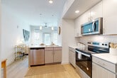 This well-designed 2-bedroom, 2-bathroom residence in Austin, TX offers a thoughtful layout that maximizes every square foot. The open-concept kitchen and living area serves as the heart of the home, featuring stainless steel appliances — including a refrigerator with ice maker, electric range, built-in microwave, and dishwasher — paired with two-tone cabinetry, white quartz countertops, subway tile backsplash, and a peninsula with pendant lighting. Light wood flooring flows throughout, complementing the bright, airy atmosphere created by large windows and recessed lighting. The living area provides a comfortable, open setting with a ceiling fan overhead. Both bedrooms are well-proportioned, with the primary bedroom offering a walk-in closet equipped with wire shelving. The two bathrooms are clean and functional, each featuring a tub-shower combination with white tile surround and wood-tone accents. A dedicated laundry area with a full-size washer and dryer adds everyday convenience. The entryway also provides additional storage. The overall aesthetic is modern and neutral, with clean lines and contemporary finishes throughout, making this Austin residence a functional and stylish home.