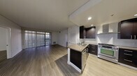 Located on Chandler Boulevard in the North Hollywood neighborhood of Los Angeles, this single-floor unit presents a contemporary design with a cohesive blend of dark cabinetry, light flooring, and modern finishes throughout.

The open-concept kitchen and living area form the heart of the space. The kitchen features a central island with an integrated sink, dark espresso cabinetry with sleek hardware, white subway tile backsplash, a stainless steel gas range with a wall-mounted hood, a stainless steel refrigerator, and recessed lighting. A pendant light above the entry adds a finishing touch.

The living area extends naturally from the kitchen, offering generous open space with wood-style flooring and access to the outdoors through large sliding glass doors framed by vertical blinds, bringing in natural light and views of the surrounding neighborhood.

The bedrooms are well-proportioned with the same wood-style flooring, clean white walls, and large windows with vertical blinds that allow ample natural light.

The bathrooms are finished with white tile flooring and dark vanity cabinetry. The primary bathroom includes a double-sink vanity with a white countertop and a large mirror, while the secondary bathroom features a single-sink vanity and a combination tub and shower with glass sliding doors.