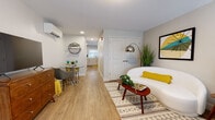 Located at 28 Temple St in Hartford, CT, this thoughtfully designed single-floor unit offers a seamless blend of modern aesthetics and functional living. Light-toned hardwood flooring runs throughout, creating a cohesive and inviting atmosphere across all spaces.

The open living area is generously proportioned, accommodating both a lounge and a dining nook. A wall-mounted split HVAC unit ensures year-round comfort. The space is anchored by a curved white sofa, a mid-century coffee table, and a bold arc floor lamp, while a compact dining set with a circular glass table occupies a cozy corner.

The bedroom is well-sized, featuring a large window that allows natural light to fill the room, a double closet with paneled doors, and direct access to the unit's entry. The kitchen is efficiently laid out in an L-shape, outfitted with white shaker-style cabinetry, white quartz countertops, a subway tile backsplash, and stainless steel appliances including a range, microwave, and dishwasher.

The bathroom features a grey vanity with a white countertop, an undermount sink with brushed nickel fixtures, and an LED-backlit mirror, contributing a clean, contemporary feel. Throughout the unit, a consistent warm neutral palette with yellow accent tones ties each room together cohesively.