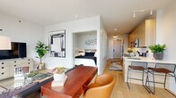 Located at 1475 N Kingsbury in Chicago's vibrant Lincoln Park/Goose Island corridor, this thoughtfully designed single-floor residence offers a seamless blend of contemporary style and functional living. Light hardwood flooring flows throughout, tying together an open-concept layout that connects the living, dining, and kitchen areas with effortless continuity.

The kitchen is a standout feature, outfitted with flat-front wood cabinetry, a herringbone tile backsplash, quartz countertops, and stainless steel appliances including a gas range. A peninsula with bar seating provides an ideal space for casual dining or entertaining. The living area is anchored by floor-to-ceiling windows that frame expansive city views, filling the space with abundant natural light.

The bedroom alcove offers a quiet, semi-private retreat with clean white walls accented by sculptural wall art. The bathroom is finished with large-format tile, a frameless glass walk-in shower, and a warm wood vanity. A dedicated workspace with room for a full desk setup adds practical versatility. Textured accent walls and curated greenery enhance the modern aesthetic throughout, creating a polished yet inviting atmosphere ideal for urban living.