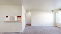 This single-floor, one-bedroom, one-bathroom unit in Fort Gratiot, Michigan, offers a practical and well-organized layout designed to maximize everyday functionality. The living area is generously proportioned, featuring soft wall-to-wall carpeting, neutral cream-toned walls, and two large windows dressed with vertical blinds that allow natural light to fill the space. The open sightlines from the living area extend through a central hallway, creating a connected and airy feel throughout.

The galley-style kitchen is efficiently designed with rich medium-toned wood cabinetry lining both walls, offering ample upper and lower storage. Light countertops provide workspace alongside a stainless steel sink, and white appliances — including a refrigerator, electric coil range, and dishwasher — complete the setup. Tile flooring runs throughout the kitchen, adding durability. A pass-through breakfast bar connects the kitchen to the living area, enhancing the open flow of the unit.

The bedroom is a comfortable, carpet-floored retreat illuminated by two windows with vertical blinds, providing natural light and outdoor views. The full bathroom includes a single-sink vanity with wood cabinetry, a large mirror, light tile flooring, and a tub-shower combination with white tile surround. Overall, the unit presents a clean, neutral palette suited for easy personalization.