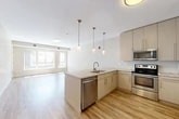 Located at 140 Seneca Way in Ithaca, NY, this one-bedroom, one-bathroom residence offers a well-designed single-floor layout with a clean, modern aesthetic. The open-concept kitchen and living area form the heart of the home, featuring light hardwood flooring that enhances the bright, airy atmosphere. The kitchen is equipped with stainless steel appliances — including a refrigerator, electric range, microwave, and dishwasher — complemented by light-toned cabinetry reaching to the ceiling and striking stone countertops with a marble-like pattern. A peninsula with pendant lighting overhead provides additional prep space and defines the transition into the living area. The living room benefits from a wide bank of windows that invite natural light and offer views of the surrounding greenery. The generously sized primary bedroom features soft carpeting, a large closet, and a window overlooking the outdoors, creating a quiet and comfortable retreat. A connecting hallway leads to the full bathroom, which includes a tub-shower combination and tile flooring. The overall design is consistent throughout, with neutral tones and contemporary finishes contributing to a cohesive and inviting living environment.