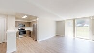 Located at 7120 Society Drive in Claymont, Delaware, this single-floor, 1-bedroom, 1-bathroom residence offers a thoughtfully designed layout with modern finishes throughout. The open-concept living and dining area is bathed in natural light, courtesy of a large sliding glass door that leads to a private balcony overlooking a green outdoor setting. Light wood-tone luxury vinyl plank flooring extends throughout the main living spaces, lending a clean, contemporary feel.

The kitchen is efficiently designed with warm wood-tone cabinetry, stainless steel appliances including a refrigerator, range, and built-in microwave, plus a skylight that brightens the space. A white breakfast bar peninsula connects the kitchen to the living area, creating a seamless flow ideal for both everyday living and entertaining.

The spacious bedroom features soft carpeting, a ceiling fan, and a sliding closet, offering ample storage. Conveniently accessible from the bedroom is an in-unit washer and dryer, adding a practical touch to daily life.

The bathroom is finished with large-format tile surrounding the soaking tub and shower, complemented by a crisp white vanity and light wood-tone flooring. Clean neutral tones and modern hardware complete the polished look throughout this well-maintained residence.