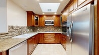 Located at 11100 Riverside Dr in the Studio City neighborhood of Los Angeles, this well-appointed 2-bedroom, 2-bathroom residence offers a thoughtfully designed single-floor layout. The kitchen is a standout feature, showcasing rich wood cabinetry, granite countertops, a mosaic tile backsplash, and a full suite of stainless steel appliances — including a gas cooktop, built-in microwave, wall oven, and refrigerator. A skylight bathes the kitchen in natural light, complemented by recessed lighting and classic tile flooring. The living room features warm hardwood floors, crown molding, and large windows that invite abundant natural light and outdoor views of the surrounding neighborhood. The generously sized primary bedroom is carpeted for comfort, finished with crown molding, and includes direct access to a private balcony as well as a dedicated walk-in closet with built-in shelving. The second bedroom also features plush carpeting, crown molding, and a window with pleasant outdoor views. Both bathrooms are finished with neutral tile and include tub-shower combinations with glass enclosures. A dedicated closet rounds out the functional layout of this comfortable Los Angeles residence.