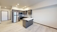 Located in Tumwater, Washington, this two-bedroom, two-bathroom single-floor residence offers a well-designed layout with a clean, contemporary aesthetic throughout. The open-concept kitchen and living area serves as the heart of the home, featuring dark espresso cabinetry, a tiled backsplash, light quartz countertops, stainless steel appliances including a refrigerator, range, microwave, and dishwasher, and a central island with additional storage. Light wood-style flooring flows through the main living areas, complementing the neutral wall tones and dark baseboards. A large window allows natural light to fill the living space, creating a bright and welcoming atmosphere. Both bedrooms are carpeted and offer a comfortable, quiet retreat, each with windows providing outdoor views. The primary bedroom includes its own closet, while additional closets throughout the unit provide ample storage. One bathroom features a combination tub and shower, while the second bathroom doubles as a dedicated laundry room with a stacked washer and dryer unit. The hallway connects all rooms efficiently, completing this thoughtfully arranged and move-in-ready residence.