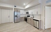 Located at 18412 Homestead Ave in Cutler Bay, FL, this thoughtfully designed 3-bedroom, 2-bathroom residence offers a clean, modern aesthetic throughout its single-floor layout. Light wood-look flooring flows seamlessly through the living areas and bedrooms, complemented by crisp white walls and abundant recessed lighting that create a bright, welcoming atmosphere.

The kitchen is a standout feature, showcasing two-tone cabinetry with white upper cabinets and warm wood-finish lower cabinets, white quartz countertops, a subway tile backsplash, and a full suite of stainless steel appliances including a French door refrigerator, range, microwave, and dishwasher.

The primary bedroom offers a comfortable footprint with direct access to a walk-in closet. The en-suite bathroom features a large vanity with white countertops, modern matte black hardware, a wide mirror with contemporary lighting, and a glass-enclosed shower. The second bathroom includes a tiled tub-shower combo, a matching vanity, and a tall linen cabinet for extra storage.

The additional bedrooms are bright and well-proportioned, each with closets and windows framing views of the surrounding Cutler Bay neighborhood with glimpses of palm trees. A connecting hallway ties all rooms together for a functional, efficient floor plan.