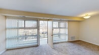 This 2-bedroom, 1-bathroom residence offers a thoughtfully organized single-floor layout designed for comfortable everyday living. The combined living and dining area serves as the heart of the home, featuring plush carpeting, a ceiling fan, and two large sliding glass doors that open to an outdoor balcony, flooding the space with natural light and providing open views of the surrounding neighborhood. The kitchen is efficiently designed with dark cabinetry, light countertops, wood-look flooring, and white appliances including a range and refrigerator. A separate pantry closet adjacent to the kitchen provides additional storage. The primary bedroom is a generously sized retreat featuring two wide windows, a ceiling fan, and soft carpeting, while the secondary bedroom offers its own window for natural light along with a dedicated closet. Three closets throughout the home, including a spacious walk-in with built-in shelving, ensure ample storage throughout. The full bathroom is clean and functional, featuring white cabinetry, a vanity mirror with overhead lighting, white tile wainscoting, and a shower-tub combination. Warm neutral tones carry consistently throughout the space, creating a cohesive and inviting ambiance.