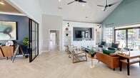 Located at 221 Embassy Dr in Fort Mill, SC, this single-floor community amenity space offers a thoughtfully designed environment for both relaxation and activity. The living room serves as the centerpiece, boasting soaring vaulted ceilings, herringbone-patterned light wood flooring, and a built-in media wall flanked by open shelving. Sleek black-framed glass doors add a modern industrial touch, while ceiling fans and recessed lighting ensure year-round comfort. An adjacent area features a communal dining table and a built-in workstation lined with computers, accented by a striking black-and-white photographic mural that pays homage to local history. The kitchenette nearby is outfitted with bold forest-green cabinetry, open shelving, a microwave, and a sink, making it ideal for resident gatherings. The spacious exercise room is a standout feature, divided into distinct workout zones. One area houses treadmills, an elliptical, and a weight rack against teal-accented walls, with large windows overlooking an outdoor pool. A secondary fitness zone offers a cable machine, punching bag, and dual water fountains. Abundant natural light throughout, views of the surrounding greenery, and a clean, modern aesthetic make this a welcoming and highly functional community facility.