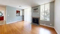 Located at 1215 N Cherokee Ave in the heart of Los Angeles, CA, this one-bedroom residence offers a well-organized, efficient floor plan across a single level. Warm-toned hardwood flooring flows consistently throughout the living areas and bedroom, lending a cohesive and inviting feel to the entire space.

The open living room serves as the focal point of the home, highlighted by a tile-surround fireplace and large vertical-blind-covered windows that invite generous natural light and views of the surrounding neighborhood. A wall-mounted A/C unit ensures year-round comfort. The space connects seamlessly to the kitchen via a pass-through counter, making the layout feel open and functional.

The kitchen is well-appointed with rich, dark cherry wood cabinetry, dark granite countertops, tile flooring, and a gas range. A window above the sink area brings in natural light and overlooks greenery outside, adding a pleasant ambiance to meal preparation.

The bedroom is a quiet, well-lit retreat featuring the same warm hardwood flooring, neutral walls, a textured ceiling, and a large window dressed with vertical blinds, offering both natural light and privacy.

Throughout the unit, a neutral gray and white color palette, textured ceilings, and clean white baseboards create a consistent, move-in-ready aesthetic ideally suited for urban Los Angeles living.