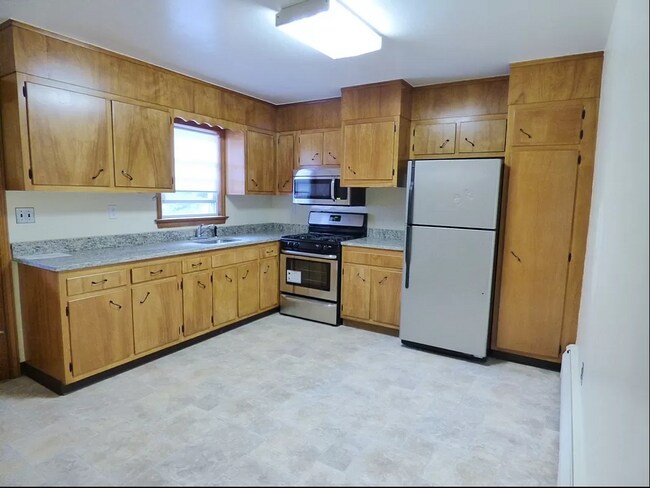 Eat-in kitchen with gas range, stainless steel appliances, and ample storage. - 3 Grange St