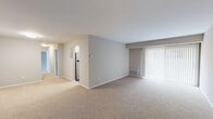 This thoughtfully designed 2-bedroom, 1-bathroom residence offers a comfortable and functional single-floor layout. The open living area is finished with neutral-toned carpet and soft gray walls, creating a clean, versatile canvas. A large sliding glass door fitted with vertical blinds allows abundant natural light to fill the space and provides access to the outdoors.

The kitchen is a standout feature, boasting white shaker-style cabinetry, granite countertops, stainless steel appliances including a range, microwave, and refrigerator, and light wood-look flooring. An in-unit washer and dryer add everyday convenience.

The primary bedroom is generously sized with carpeted floors, a natural light source via a window with blinds, and a spacious walk-in closet equipped with dual wire shelving systems for ample storage. The second bedroom is equally comfortable, also featuring carpet and easy access to the shared hallway. The full bathroom includes a tiled tub-shower combination with a curved curtain rod, wood-look flooring, and clean white fixtures.

With four closets throughout, a central hallway connecting all rooms, and a cohesive neutral color palette, this residence delivers practical, move-in-ready living in a well-organized floor plan.