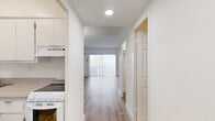 Located at 850 W 49th St, Unit 707, in Hialeah, FL, this compact and efficiently designed unit offers a well-organized single-floor layout comprising a living room, kitchen, full bathroom, closet, and hallway. The living area is bright and open, featuring light wood-tone laminate flooring and crisp white walls that maximize the sense of space. A sliding glass door leads directly to a private balcony, flooding the room with natural light and offering elevated outdoor views of the surrounding Hialeah landscape. A wall-mounted mini-split air conditioning unit ensures comfortable climate control throughout. The kitchen is clean and functional, equipped with white cabinetry, a stainless steel single-basin sink with a brushed nickel faucet, and light composite countertops, alongside a white electric range. A central hallway connects the main rooms and is illuminated by recessed ceiling lighting. The bathroom features white tile walls, a combination tub and shower with brushed gold fixtures, a mirrored vanity, and tile flooring, offering a tidy and utilitarian design. A dedicated closet provides practical storage. The overall aesthetic is clean, minimal, and move-in ready, making this unit a straightforward and functional living space.