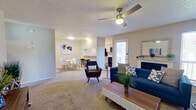 This 2-bedroom, 1-bathroom residence is thoughtfully laid out on a single floor, offering a functional and comfortable living experience. The open-concept living area serves as the heart of the home, featuring plush carpeting, a ceiling fan with integrated lighting, and a fireplace flanked by windows that invite natural light throughout the day. The living space flows seamlessly into a dining area and a compact kitchen equipped with dark appliances, white cabinetry, and a breakfast bar with seating.

The primary bedroom is a spacious retreat with soft carpet flooring, a dedicated closet, and a window providing natural light. The second bedroom is equally well-appointed and showcases a standout sliding barn door with a gray and white finish, adding a distinctive farmhouse-inspired design element to the room. Both bedrooms offer comfortable proportions suited for rest and relaxation.

The shared bathroom features a full tub and shower combination with built-in wall shelving. A dedicated closet provides additional storage. Textured ceilings are consistent throughout the home, and the neutral color palette of soft grays and warm whites creates a clean, cohesive ambiance that works well across all rooms.