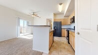 Located at 7590 Little Fox Ln in Wellington, Colorado, this single-floor, one-bedroom, one-bathroom residence offers a well-organized and functional layout. The open-concept kitchen and living room serve as the heart of the home, where light oak cabinetry, dark countertops, and black appliances — including a refrigerator with ice dispenser, electric range, and built-in microwave — are complemented by tile flooring. A peninsula with a breakfast bar connects the kitchen to the carpeted living area, which features a ceiling fan and a sliding glass door that invites natural light and outdoor access. The bedroom is a comfortable, sunlit retreat with plush carpeting, a ceiling fan, large windows offering neighborhood views, and a sliding double-door closet with built-in shelving. The full bathroom includes a soaking tub and shower combination with built-in shelving, tile flooring, and clean white finishes. A dedicated laundry room with side-by-side washer and dryer units and overhead shelving provides added convenience. Throughout the home, neutral tones, tile and carpet flooring, and generous window placement create a bright, cohesive living environment.