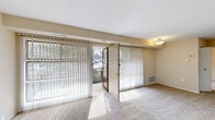 This one-bedroom, one-bathroom unit offers a thoughtfully arranged single-floor layout that maximizes every square foot of its compact footprint. The combined living and dining area serves as the heart of the unit, featuring neutral-toned carpet, a flush-mount ceiling light, and large sliding glass doors dressed with vertical blinds that open to an outdoor balcony. The balcony access floods the space with natural light and provides outdoor views of surrounding greenery.

The kitchen is efficiently designed with warm wood-toned cabinetry, light speckled countertops, a double sink, and white appliances including a range and refrigerator. Dark wood-style vinyl flooring grounds the kitchen area, providing a clean contrast to the carpeted living spaces. An open shelving unit adjacent to the kitchen offers convenient pantry storage.

The bedroom is a comfortable, well-proportioned retreat featuring soft carpet, a ceiling fan with integrated lighting, and a window that invites natural light. Multiple closets — including a walk-in — provide ample storage. The bathroom is clean and straightforward, featuring a tub-shower combination with white tile surround, a vanity with under-sink cabinet, a medicine cabinet mirror, and wood-style vinyl flooring. Three additional closets throughout the unit further enhance the overall storage capacity of this practical and livable space.