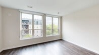 Located at 101 Washington St in Conshohocken, PA, this efficiently designed single-floor unit makes excellent use of its compact footprint. The open living area is anchored by rich hardwood flooring that extends throughout the space, creating a warm and cohesive aesthetic. Large windows flood the room with natural light and offer views of the surrounding neighborhood, enhancing the sense of openness.

The modern kitchen is a standout feature, outfitted with a full suite of stainless steel appliances including a refrigerator, dishwasher, gas range, and microwave. Two-tone cabinetry combines high-gloss white upper cabinets with wood-grain lower cabinets, complemented by a clean white countertop, an undermount sink, and a subtle subway tile backsplash. Track lighting above highlights the kitchen's contemporary design.

The bathroom is finished to a high standard, featuring marble-patterned tile in the walk-in shower with a glass enclosure, wood-look floor tile, and chrome fixtures and grab bars, lending the space a clean, spa-like quality.

A dedicated closet provides practical storage. The unit also includes a hallway connecting the entry to the main living and kitchen areas, with white panel doors maintaining a consistent, polished look throughout. The overall ambiance is modern, clean, and move-in ready.