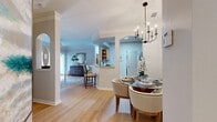 This single-floor, 3-bedroom, 2-bathroom home offers a thoughtfully designed open-concept layout that maximizes both functionality and style. The living room serves as the heart of the home, showcasing crown molding, light hardwood flooring, and a large sliding glass door that floods the space with natural light and provides access to an outdoor area. The living room flows naturally into a dedicated dining area, anchored by an elegant candle-style chandelier and framed by arched architectural details that add character throughout.

The kitchen features light wood cabinetry, stone-look countertops, tile flooring, a tile backsplash, and black appliances including a range, microwave, dishwasher, and refrigerator. A convenient pass-through peninsula connects the kitchen to the dining space, enhancing the open feel.

The primary bedroom offers comfortable proportions with plush carpeting and access to a well-appointed en-suite bathroom. The primary bath includes a long vanity with stone countertops, white cabinetry, and tile flooring. A spacious walk-in closet with built-in wire shelving and organizational systems provides ample storage. The additional bedrooms are cozy and carpeted, served by a second full bathroom. Arched doorways and consistent finishes throughout lend the home a cohesive, refined ambiance.