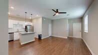 Located at 1851 Encantado Way in Kissimmee, Florida, this single-story 2-bedroom, 2-bathroom home offers a thoughtfully designed layout with modern finishes throughout. The open-concept living, dining, and kitchen area serves as the heart of the home, featuring warm hardwood-style flooring, neutral gray walls, and a ceiling fan with light. The kitchen is outfitted with crisp white shaker cabinets, granite countertops, a subway tile backsplash, stainless steel appliances including a refrigerator, and pendant lighting over the counter, providing both style and functionality. Natural light filters through slatted window blinds in the living area, creating a bright and airy atmosphere. Both bedrooms are carpeted for comfort and include ceiling fans and closets. The spacious primary bedroom offers natural light through a window and direct access to a dedicated closet. The bathrooms are finished with granite-topped white vanities and tile flooring; one features a glass-enclosed shower. Additional conveniences include a laundry area, utility room, hallway, and an outdoor patio. The home presents a clean, move-in-ready aesthetic with a cohesive neutral palette throughout.