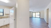 Located at 235 Croton Ave in Lantana, Florida, Unit 3 is a well-appointed single-floor residence that combines clean, modern finishes with a bright and airy atmosphere throughout. Light wood-style flooring flows consistently across the living areas, bedrooms, and hallways, creating a cohesive and welcoming environment.

The kitchen stands out with crisp white shaker cabinetry, granite-look countertops, and white appliances including a refrigerator, dishwasher, range, and under-cabinet ventilation. A pass-through window connects the kitchen to the living area, enhancing the open feel of the space. Natural light fills the kitchen through a window overlooking the outdoors.

The living area is spacious and open, featuring a ceiling fan with light fixture and large sliding glass doors that lead to a private balcony with outdoor views. Additional rooms, likely serving as bedrooms, are well-sized with ceiling fans, natural light from window-blind-fitted windows, and ample floor space.

A hallway connects the bedrooms and bathrooms, which include a vanity with granite countertops, white cabinetry, brushed gold hardware, and a tiled tub-shower combination. In-unit laundry with louvered closet doors is also accessible from the main hallway, adding everyday convenience to this thoughtfully designed Lantana residence.