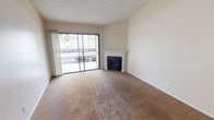 This single-floor residence offers a well-organized layout with a comfortable and functional design throughout. The living room serves as the heart of the space, featuring warm beige carpeting, a classic white-mantled fireplace, and a full-width sliding glass door that opens to a private balcony, allowing natural light to fill the room and providing views of the surrounding area. Soaring vaulted ceilings in the living and dining area add a sense of openness, while a textured ceiling treatment adds character throughout the home. The space transitions seamlessly from carpet to wood-look vinyl flooring as it flows into the kitchen and adjacent areas. The kitchen is efficiently designed with white cabinetry, granite-look countertops, a stainless steel sink, gas range, and dishwasher. A pass-through opening connects the kitchen to the living area, enhancing the open feel. The bedroom is carpeted and bathed in natural light through a generous window. The bathroom features a full-size tub and shower combo alongside a wide vanity with a speckled countertop, undermount sink, and a well-lit mirror. Overall, the space presents a clean, neutral palette well-suited for comfortable everyday living.