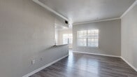 Located at 11800 City Park Central Ln in Houston, TX, this well-appointed 2-bedroom, 2-bathroom residence offers a thoughtfully designed single-floor layout. The open-concept living and dining area is bright and welcoming, featuring wood-style plank flooring, crown molding, and multiple windows with natural light streaming through slatted blinds. The kitchen is a standout feature, centered around a peninsula with granite countertops, white shaker cabinetry, a stainless steel sink, and stainless steel appliances including a refrigerator and dishwasher — all flowing seamlessly into the main living space. A private balcony extends the living area outdoors. Both bedrooms are carpeted and generously sized, with large windows that invite natural light. The spacious primary bedroom includes dual closets — one walk-in with multi-level shelving and one with bi-fold doors — providing excellent storage. Three closets are distributed throughout the unit. The two bathrooms are finished with granite-topped white vanities, brushed nickel hardware, and wood-style flooring. One bathroom features a tub-shower combination with tile surround. A hallway connects the private quarters to the main living areas, completing this clean and cohesive floor plan.