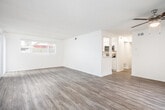 Located at 15701 Tustin Village Way in Tustin, California, this single-story unit offers a clean, updated interior with a cohesive design throughout. Light wood-style flooring runs consistently across all living areas, bedrooms, and the kitchen, creating a bright and unified aesthetic.

The open living area is generously proportioned, featuring a ceiling fan, vertical blinds covering a large window that allows natural light to fill the room, and a pass-through opening that connects seamlessly to the kitchen. The kitchen is well-appointed with white shaker-style cabinetry, light countertops, a stainless steel sink, and a full suite of stainless steel appliances including a gas range, over-the-range microwave, refrigerator, and dishwasher.

The bedrooms are comfortably sized, each featuring large windows with vertical blinds that bring in natural light, textured ceilings, and ample wall space. One bedroom includes a built-in closet with shelving for organized storage.

The bathroom is neatly finished with a wide white vanity, generous counter space, a large mirror with overhead lighting, and a tub-shower combination. Crisp white walls and clean finishes throughout the unit contribute to a bright, move-in-ready atmosphere.