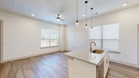 Located at 2036 Oak Grove Pkwy in Aubrey, TX, this two-story home offers a well-designed layout spread across two floors. The ground floor features an open-concept living, dining, and kitchen area filled with natural light from multiple windows. The kitchen is a standout, boasting white cabinetry, a tiled backsplash, stainless steel appliances, and a granite-topped island with a undermount sink and stylish pendant lighting. Wood-look flooring runs throughout the main level, complementing the clean, neutral palette. A staircase leads to the upper floor, where all three bedrooms are located. The primary bedroom offers generous proportions, carpet flooring, and access to a dedicated closet. The bathrooms are well-appointed, with one featuring wood-look flooring, a tub-shower combo with marble-style tile surround, and granite vanity countertops. Upstairs hallways are bright and open, with recessed lighting and ample closet storage throughout. The home also includes an attached garage and a pantry. Outside, the brick exterior is complemented by a wood-fenced yard, and the property sits within a well-maintained neighborhood community in Aubrey, TX.